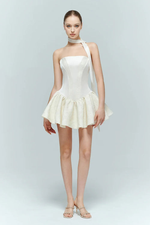 Front view of Arles white strapless mini dress with drop waist corset bodice and pleated ruffle skirt, worn with matching neck scarf.