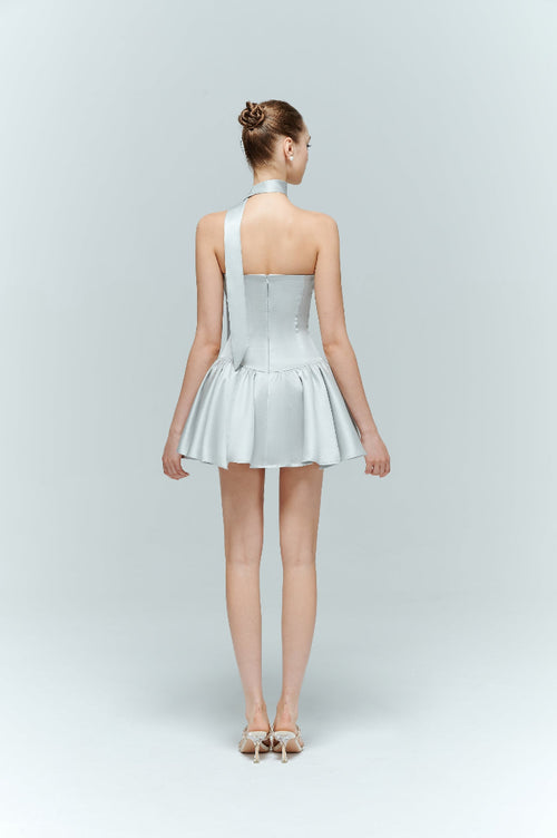 Back view of the Arles light blue corset dress, showing the concealed back zipper and trailing neck scarf on the model.