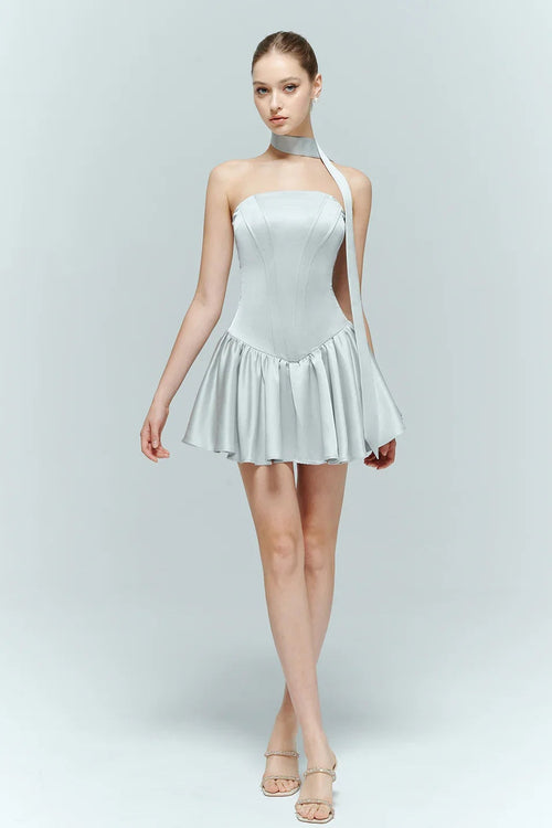 Model walking in the Arles light blue mini dress, showcasing the movement of the voluminous drop-waist jacquard skirt