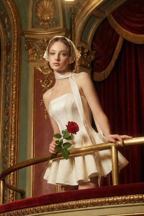 Model wearing Arles white corset mini dress on a theatre balcony holding a red rose, vintage Parisian coquette aesthetic.