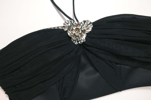 Detail shot of the signature silver emblem hardware on the center bust of the Aveline black top, perfect as going out top.