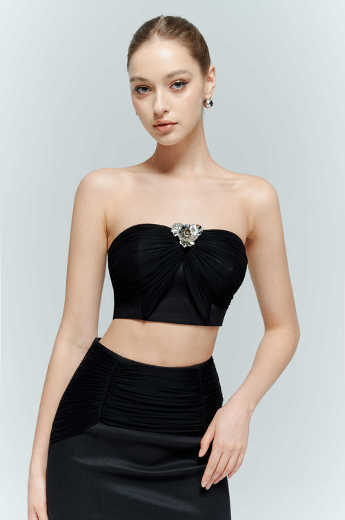 Close up view of women wearing the Artel Retro Aveline black strapless bustier top featuring elegant ruched fabric and a silver emblem