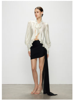 A full-body view of a model wearing the Elise elegant white ruffle tie neck blouse with long sleeves, paired with a black mini skirt.