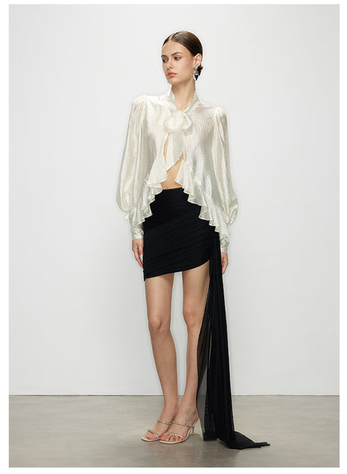 A full-body view of a model wearing the Elise elegant white ruffle tie neck blouse with long sleeves, paired with a black mini skirt.