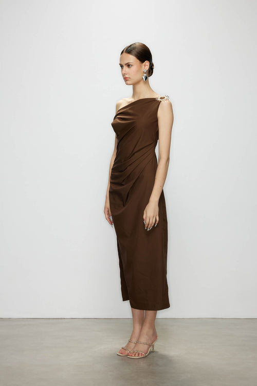 Side profile of a model wearing the high slit dress in chocolate brown, showcasing the elegant drape and sleek sleeveless cut.