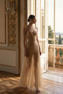 Model standing in an elegant room wearing the Celestia champagne dress, a perfectly feminine dress that makes a stunning cocktail wedding guest dress