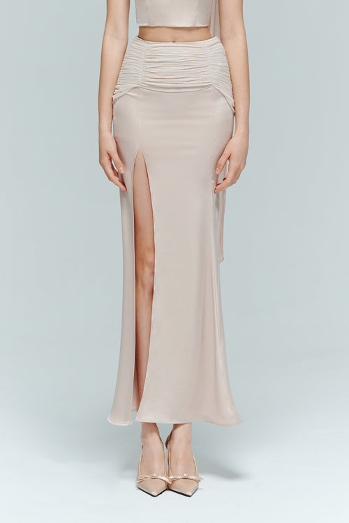 Close-up of dahlia light pink satin high waist skirt featuring a gathered waist and a dramatic thigh-high slit