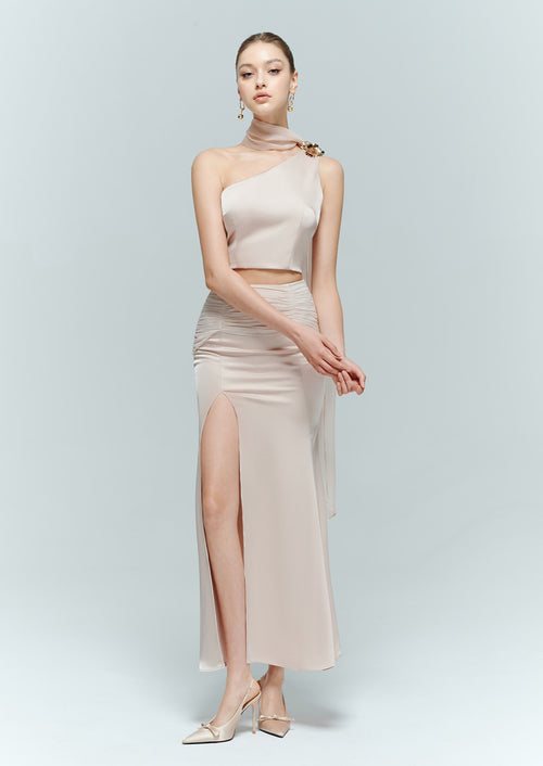 Full-length view of a model in a vintage-inspired light pink maxi skirt paired with an elegant one-shoulder top