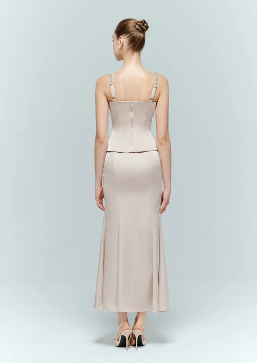 Back view of a model wearing a light pink corset top, detailing the sleek back zipper closure and cropped hem styling.