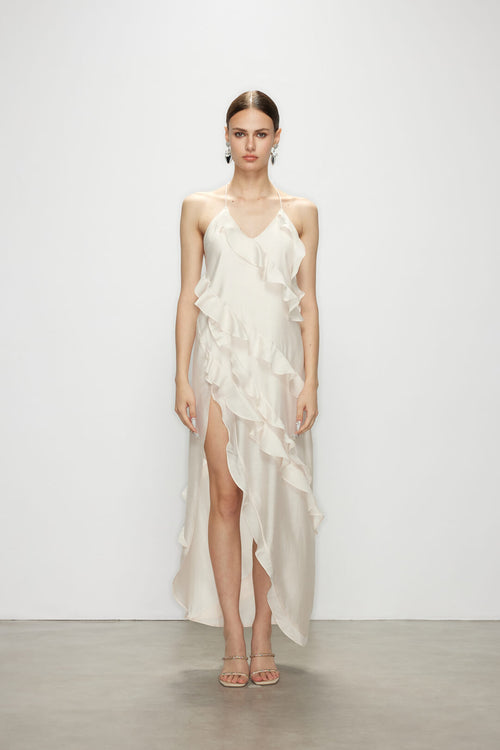 Model wearing the minimalist elegant Wavekiss white ruffle dress, featuring a high slit and cascading details.